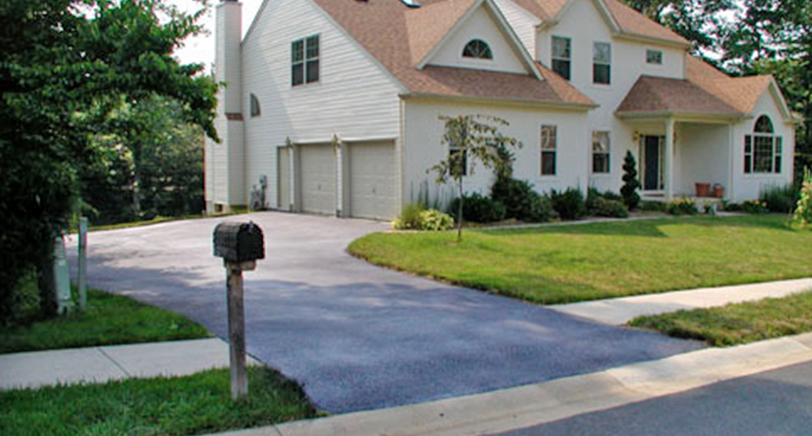 Driveway Doctors happy client with new sealcoat surface.